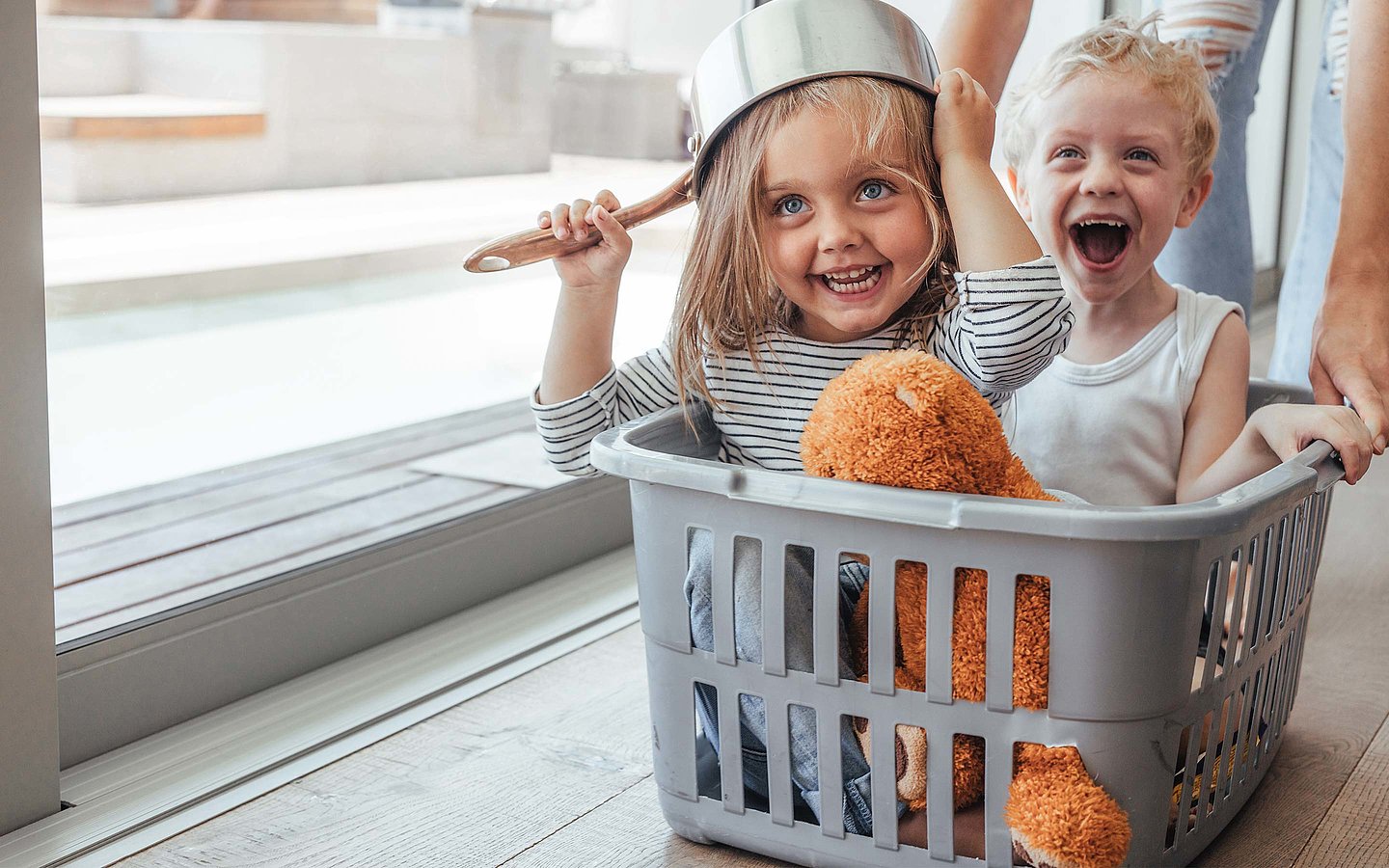 Zwei Kinder spielen in einem Wäschekorb